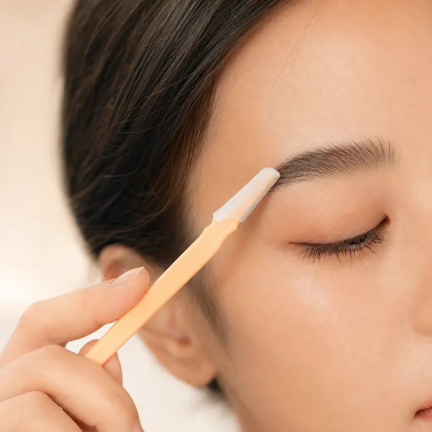 Using a Peachly razor to tidy and define the shape of an eyebrow