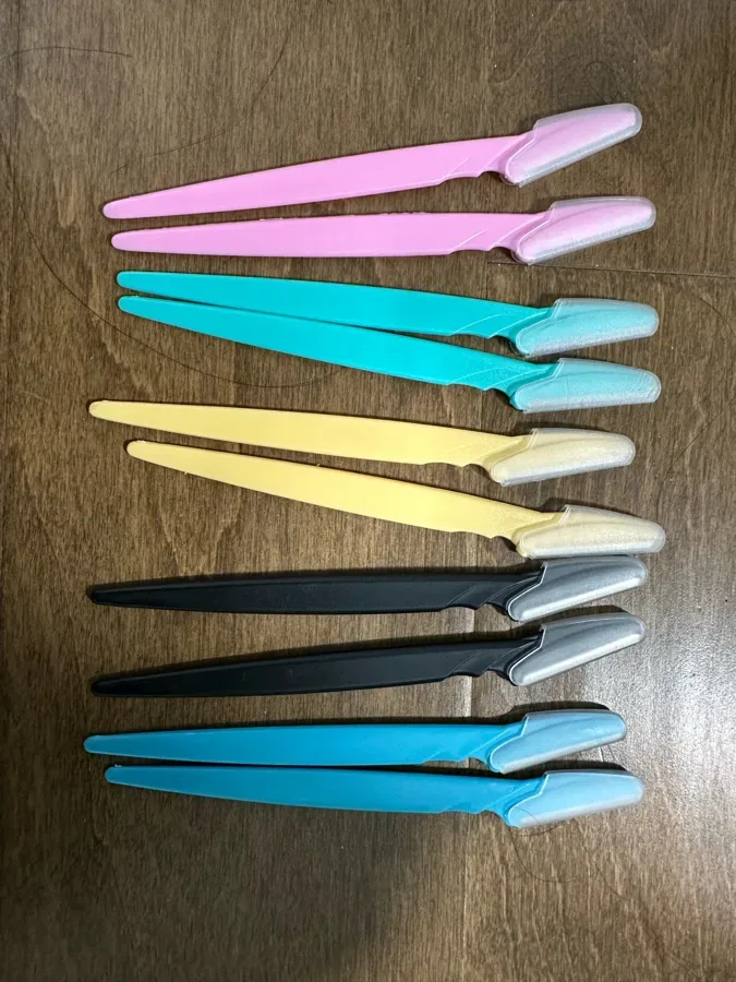 A set of Peachly dermaplane razors in assorted colors laid out on a soft surface
